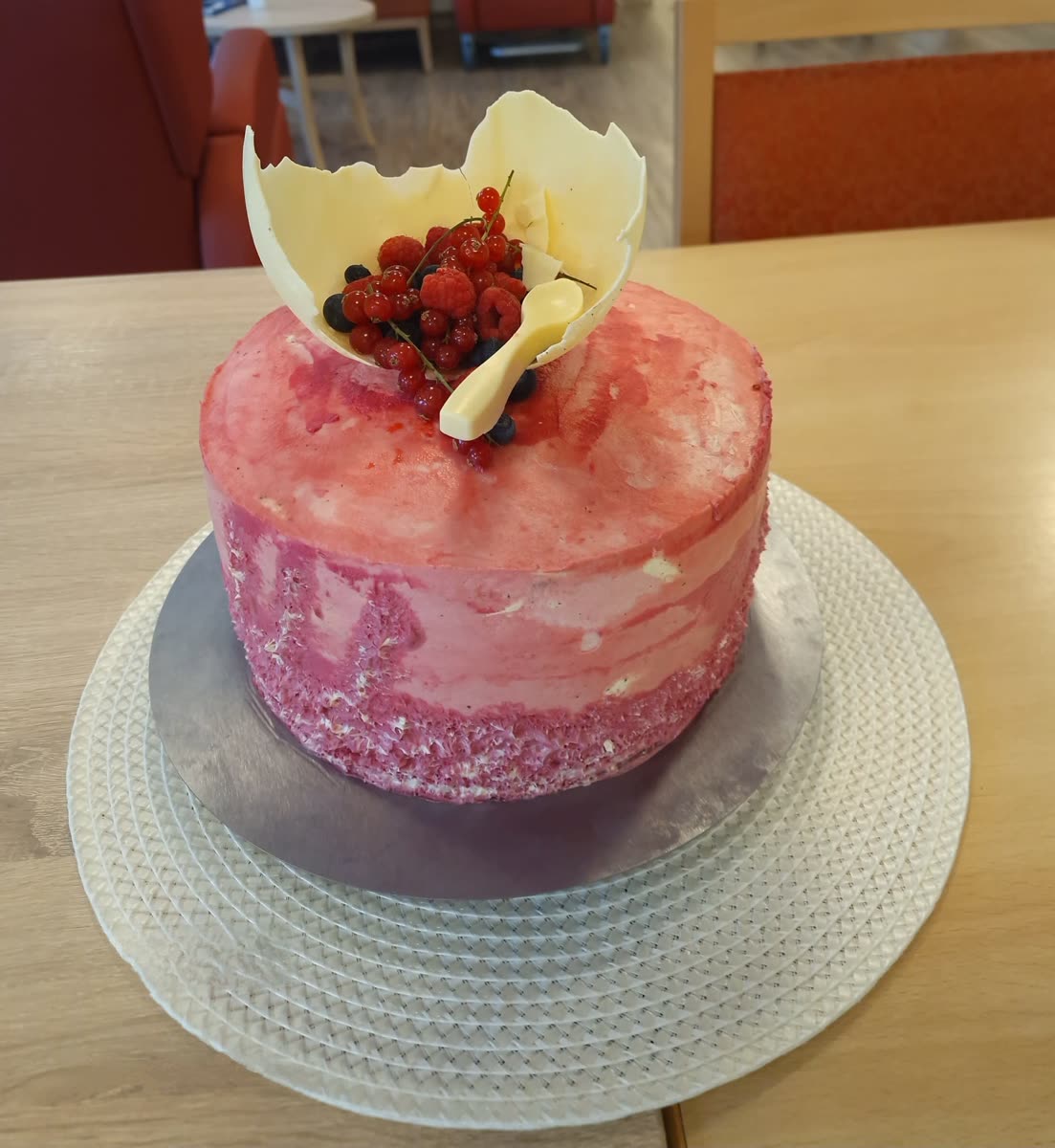 Rosafarbene Torte mit Schokoladensegel und Beeren