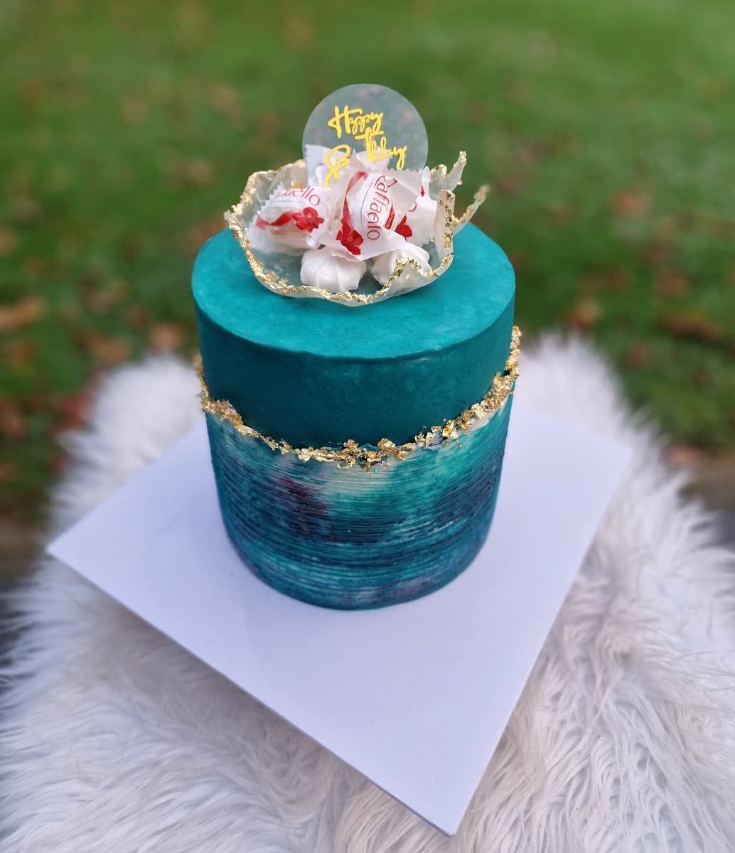 Türkise Torte mit Goldrand und Sahnehaube